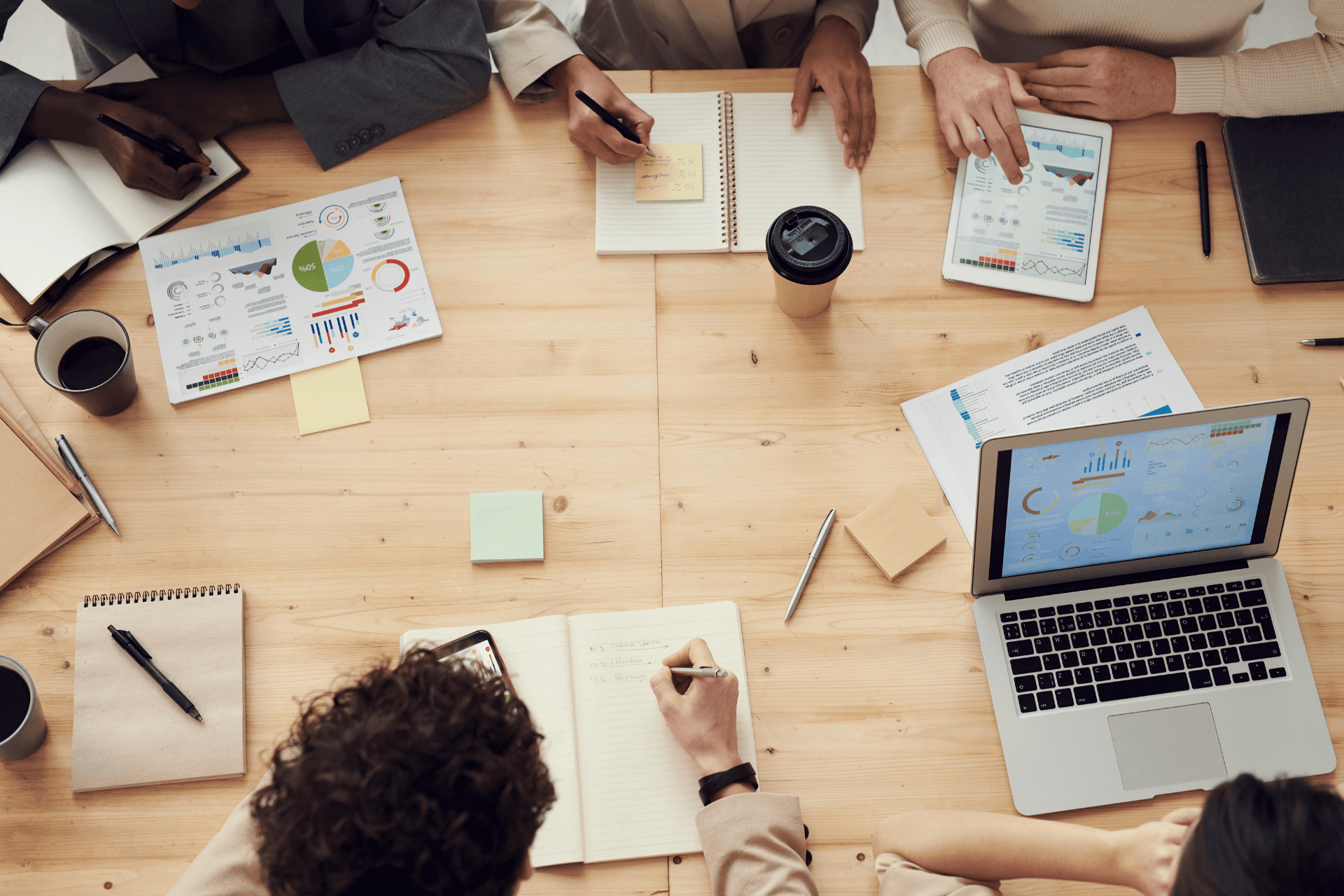 People meeting around a table with post-it notes, coffee, and charts
